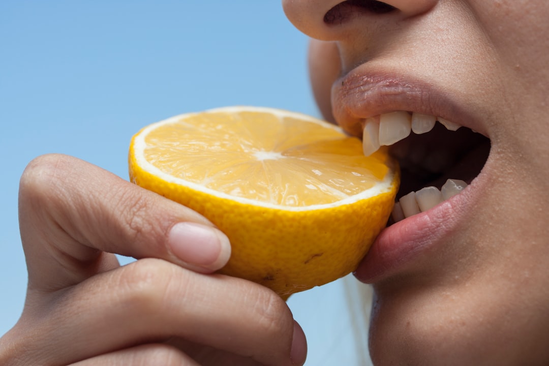 Woman biting fresh lemon slice closeup