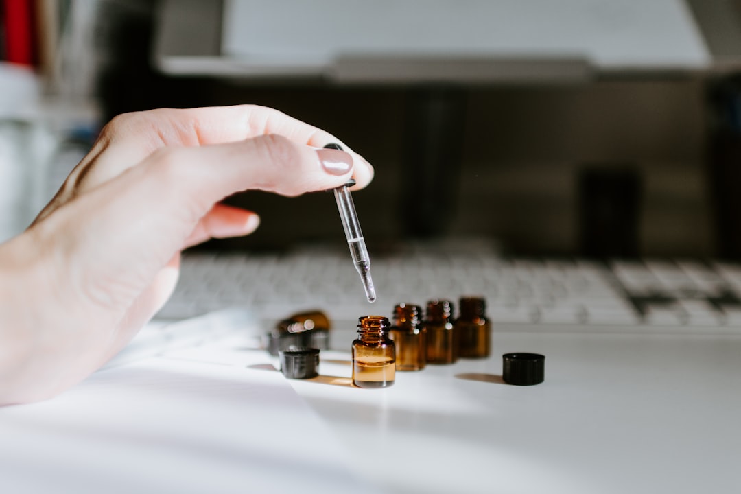 Hand holding dropper with essential oil bottles